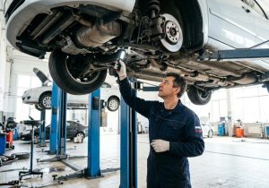 Автомеханик осматривает днище автомобиля на подъёмнике