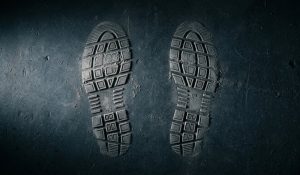 Пыльные следы подошвы обуви на тёмной поверхности