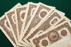 старинные сертификаты акций с орнаментом на столе
