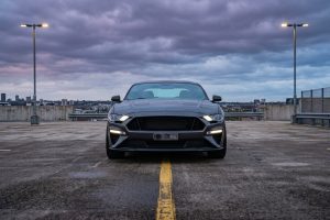 Тёмный спортивный автомобиль анфас на парковке